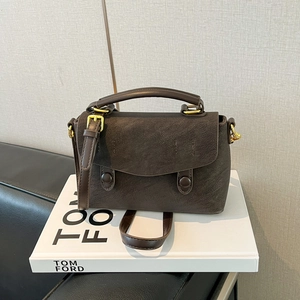 Detail of vintage dark brown crossbody bag with gold hardware on minimalist background
