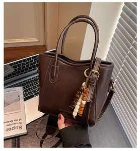 Détail d'un sac seau en cuir marron foncé avec perles en bois et une bandoulière