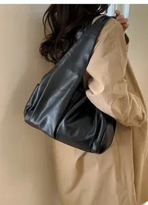 Détail du grand sac cabas plissé noir porté par un mannequin en trench-coat long