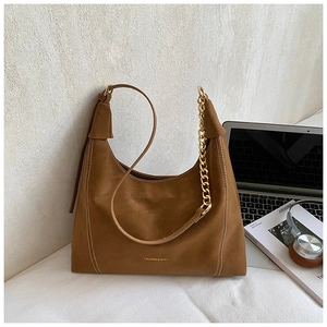 Brown vintage hobo bag with gold chain and strap displayed with fashion accessories