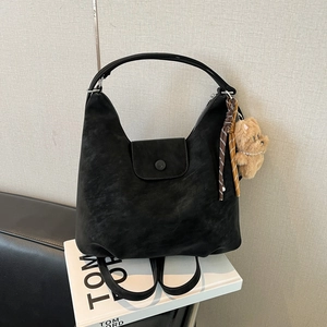 Détail d'un sac cabas en daim noir avec breloque ours sur un livre Tom Ford