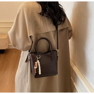 Détail du sac seau en cuir marron foncé avec charm en perles bohème et bandoulière