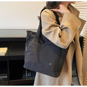 Detail view of large black nylon tote bag showing white CHUANGMI side label and strap