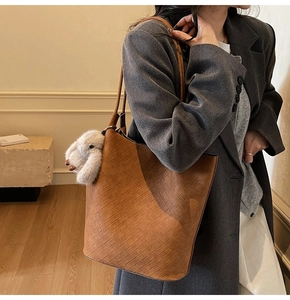 Close-up of brown woven leather tote bag texture with a cute plush bunny charm