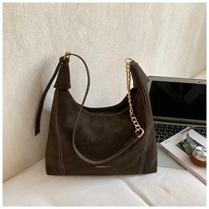 Detail of dark brown matte hobo bag featuring white stitching and gold chain strap