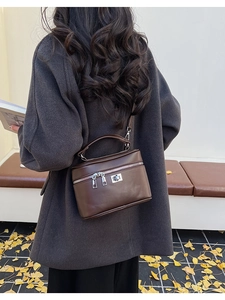 Deep brown matte leather box bag with silver hardware worn by model in a winter coat