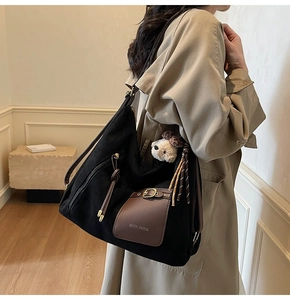 Détail d'un sac cabas en toile noire avec cuir marron et charm ours adorable