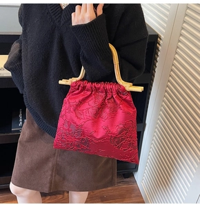 Close-up of a red satin tote bag with floral embroidery and natural bamboo handle
