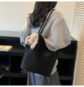 Detail of black woven tote bag with premium texture and cute plush bunny charm