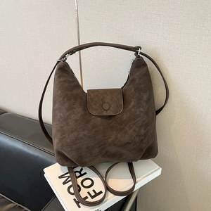 Détail du sac hobo vintage marron foncé montrant la texture du cuir mat et le bouton pression