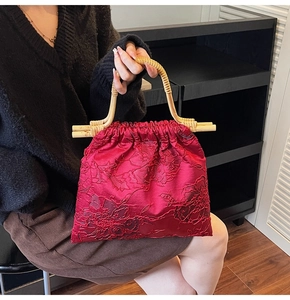 Detailed close-up of dark red floral embossed fabric with elegant bamboo top handle