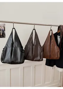 Détail de sacs fourre-tout en cuir ciré avec poches latérales en noir et marron