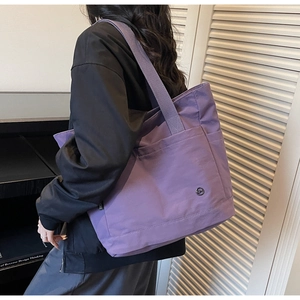 Side view of purple nylon tote bag on shoulder showing large capacity and side pockets