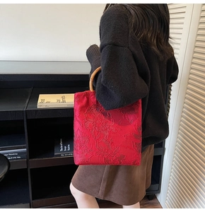 Detailed close-up of red tote bag with floral embroidery and natural bamboo handle