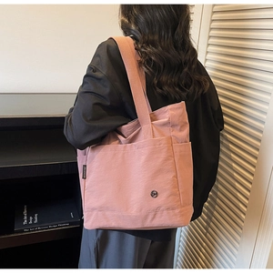 Detail view of the large capacity pink tote bag with side label and fabric strap