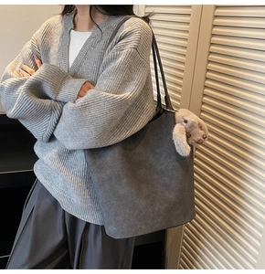 Detail view of grey woven leather tote bag with cute plush rabbit keychain and long straps