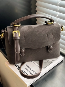 Brown retro crossbody bag with litchi grain texture on white books background