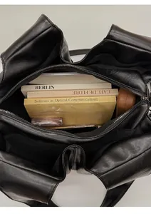 Vue de dessus montrant l'intérieur spacieux du cabas en cuir noir avec divers objets personnels