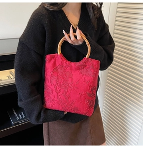 Detail view of red jacquard tote bag with natural bamboo handles and floral texture
