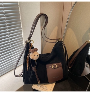 Gros plan du sac MCGK PARIS avec bandoulière en cuir marron et breloque ours