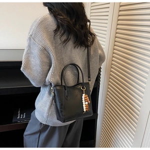 Détail du sac seau noir avec pendentif en perles et bandoulière réglable en cuir