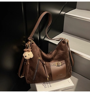 Détail du sac cabas en daim marron foncé avec boucle métallique et breloque ours