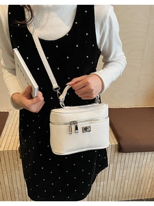 Detailed shot of white leather box bag with silver hardware and top handle for styling