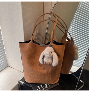 Detailed close-up of brown woven tote bag with soft suede texture and cute bunny charm