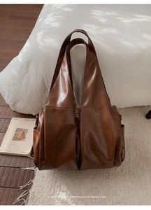 Sac cabas rétro marron foncé sur tapis beige avec bandoulière large et poches côté
