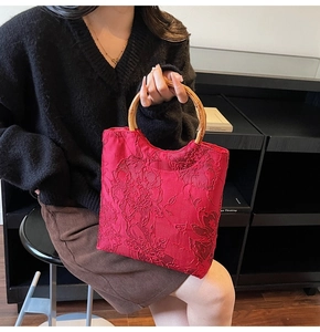 Close-up of red floral lace fabric and round bamboo handle on this stylish tote bag