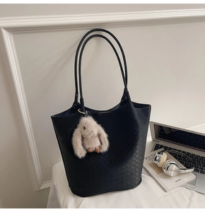 Detail of black woven texture tote bag with a cute plush bunny charm for office commute