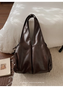 Vue détaillée du sac cabas vintage marron foncé sur un décor de literie blanche épurée