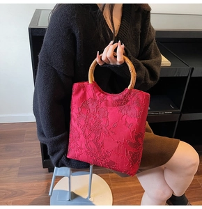 Close-up of red floral jacquard fabric tote bag with natural bamboo handle in a lifestyle setting