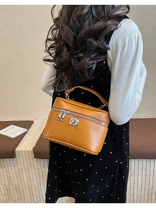 Detail of caramel leather box bag with silver hardware on a model in polka dot dress