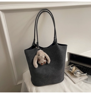 Detailed view of dark grey woven tote bag with a cute plush bunny charm and roomy interior