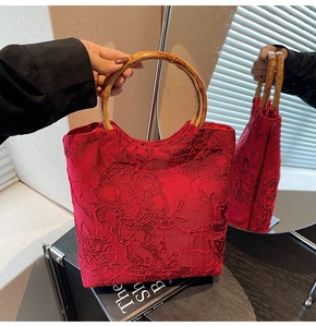 Close-up of red tote bag featuring elaborate floral embroidery and bamboo handles