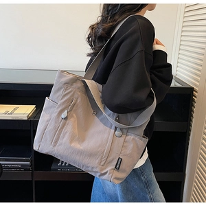 Detail of grey nylon tote bag showing wide shoulder strap and side storage pocket