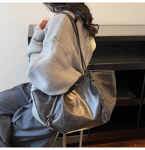 Close-up of dark grey tote bag with side knot drawstring detail and leather texture