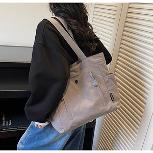 Detail view of dark grey tote bag featuring durable fabric and wide shoulder strap