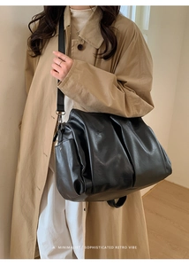 Grand sac cabas rétro noir en cuir ciré porté à l'épaule sur un mannequin chic