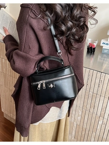 Detail of a black box handbag with silver hardware and glossy PU leather texture