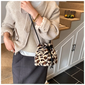 Detail of leopard print plush bucket bag with drawstring closure and leather strap