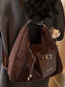 Grand sac à bandoulière en daim marron avec breloque ours porté par un mannequin en hiver