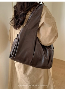 Vue latérale d'un sac cabas vintage en cuir marron foncé porté par un mannequin en salle