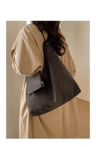 Detail view of large brown suede tote bag with matching pouch shown on a model
