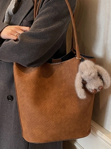 Minimalist brown woven tote bag with shoulder strap and plush charm for winter