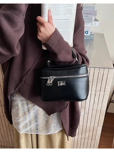 Close-up of elegant black leather box bag with silver zipper in a lifestyle setting