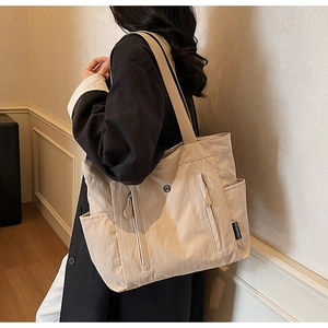 Detailed side view of high-capacity beige tote bag showing side pockets and texture