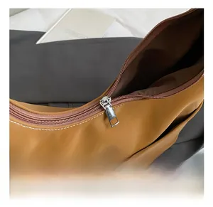 Close-up of the silver metal zipper and smooth brown leather texture on a tote bag