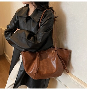 Detail shot of vintage brown leather tote bag with side drawstring knot and long strap